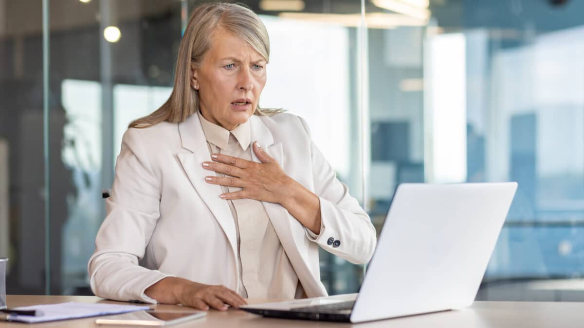 Concerned businesswoman reacting to a data breach on her laptop in a modern office setting.