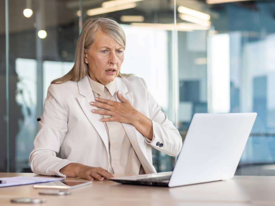 Concerned businesswoman reacting to a data breach on her laptop in a modern office setting.