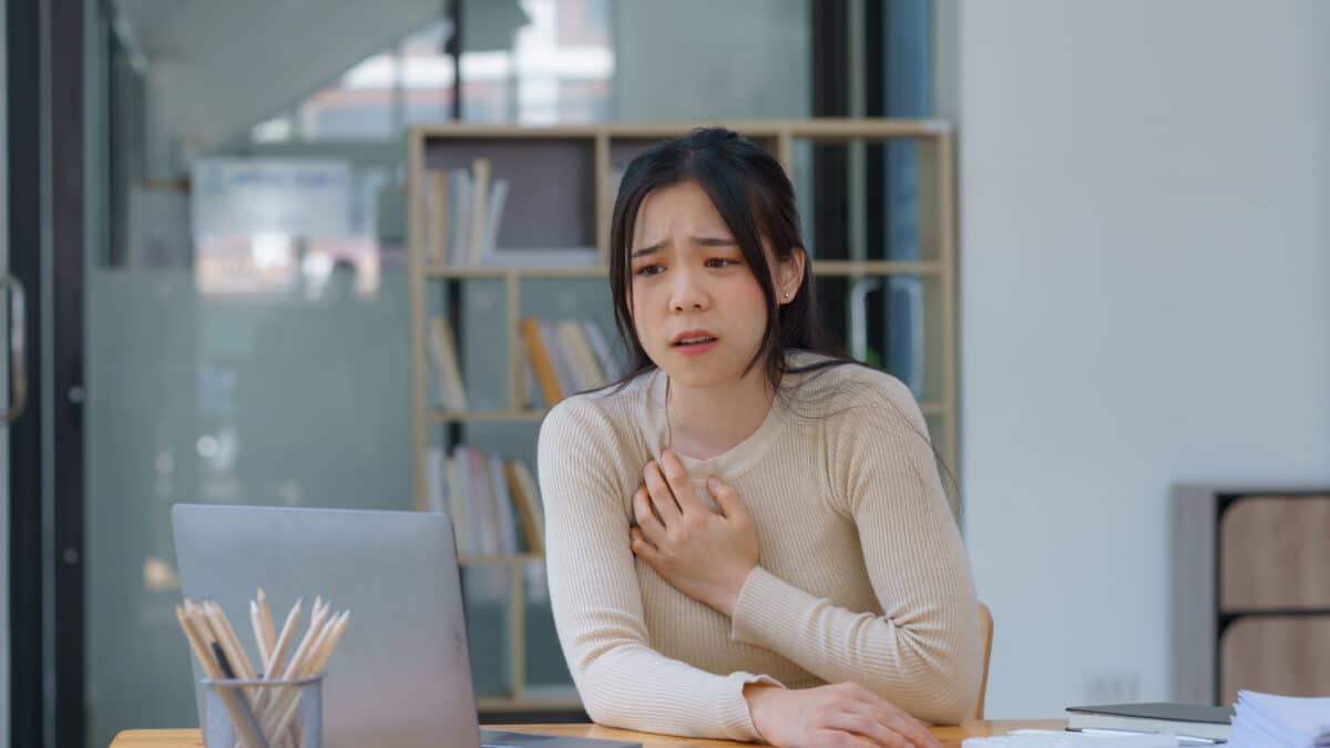 Stressed employee at desk sees malware icons on her laptop screen, representing a malware attack.