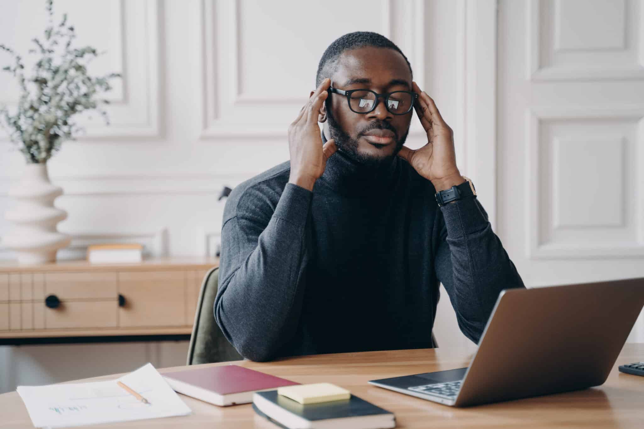 A stressed businessman at a desk with a laptop, highlighting the importance of an Incident Response Plan.