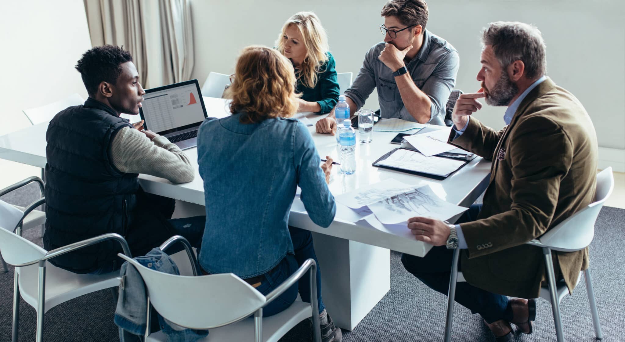 Business team meets to discuss cybersecurity strategies around a conference table in an office.