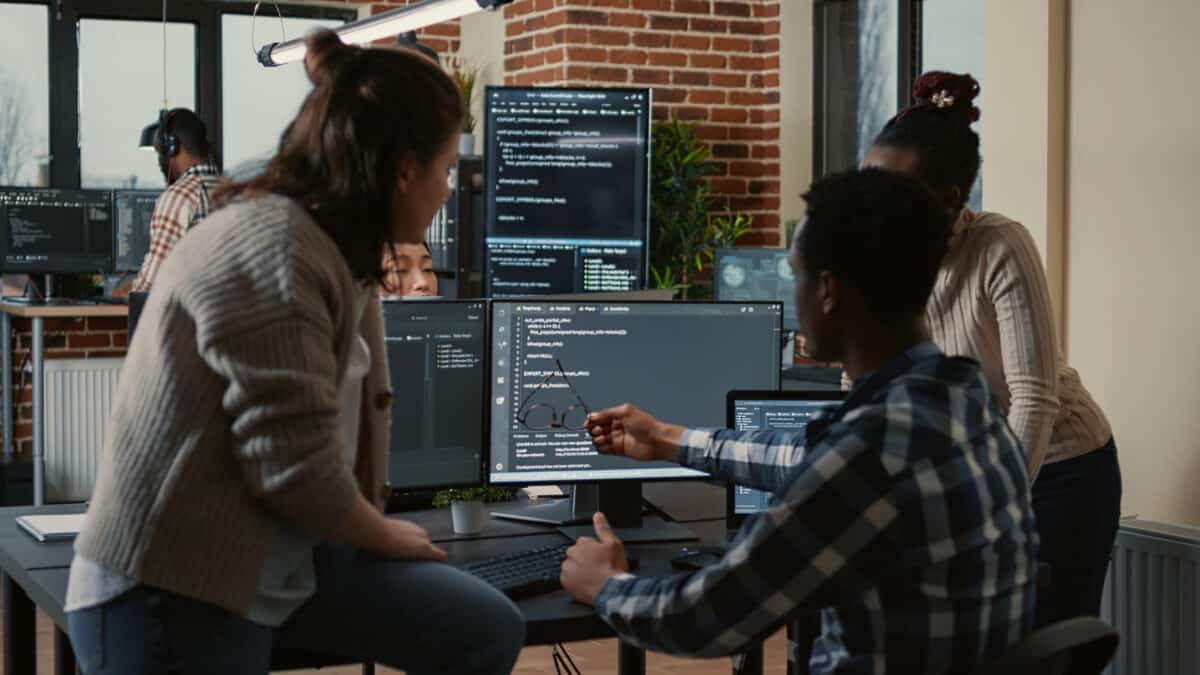 Developers work together on AI scribe technology; code is displayed on multiple computer screens.