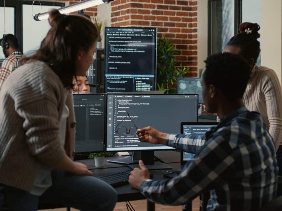 Developers work together on AI scribe technology; code is displayed on multiple computer screens.