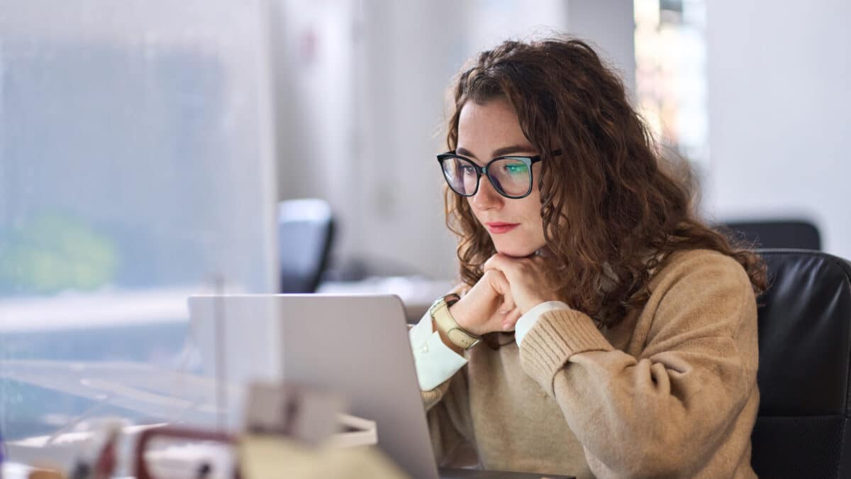 Employee reads on laptop; highlights importance of staff involvement in new cybersecurity policies.