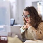 Employee reads on laptop; highlights importance of staff involvement in new cybersecurity policies.