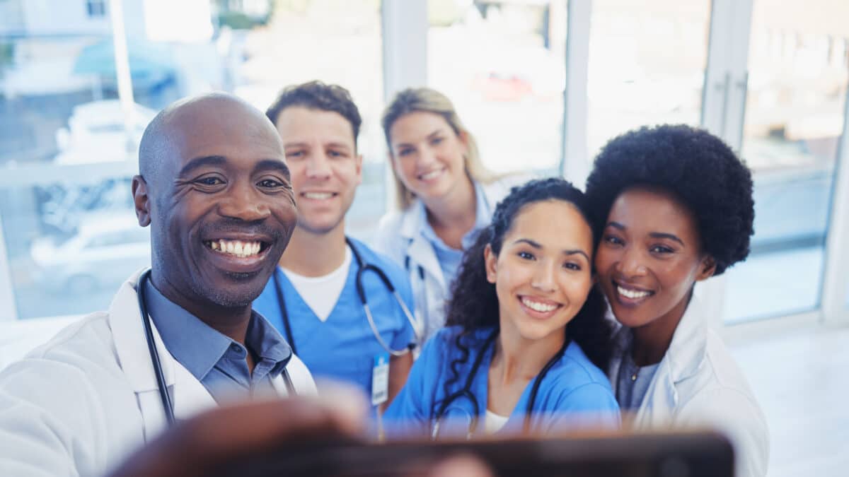 Healthcare, team and selfie by doctors at hospital, happy and proud , smile and bond on blurred background. Medical, diversity and group pose for photo, profile picture or website homepage update.