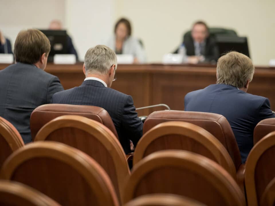 Government officials in a formal meeting; emphasizing the need for accurate, secure transcription