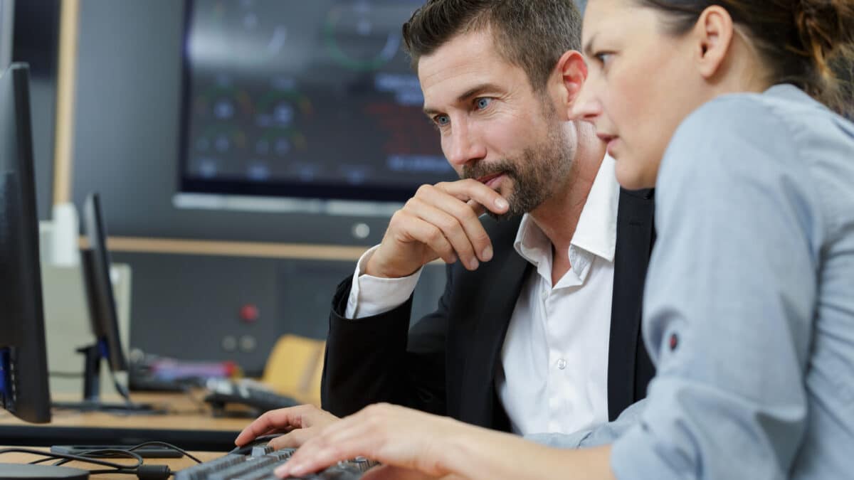 Two professionals reviewing government transcription compliance standards on a computer screen.