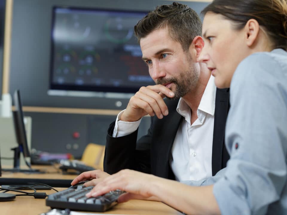 Two professionals reviewing government transcription compliance standards on a computer screen.